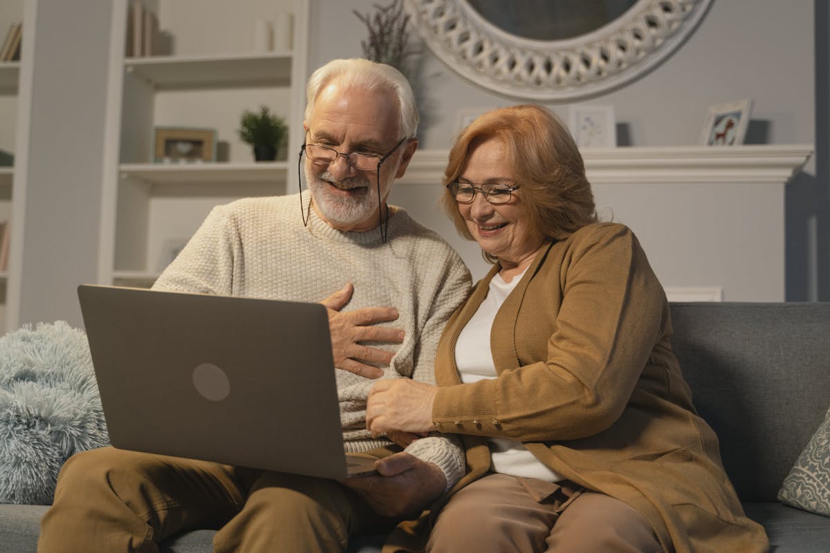 Happy retired couple celebrating their annuity contract on a laptop